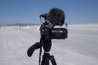 Close-up of camera on beach against sky