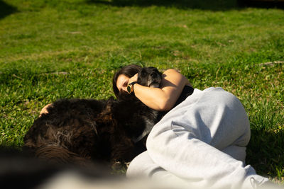 Woman embracing dog lying on grass