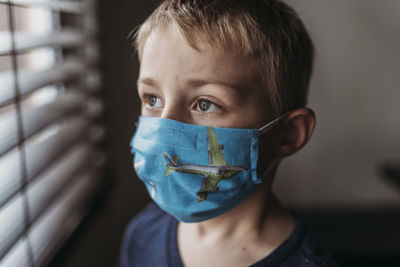 Portrait of young school aged boy with mask on with at home negative space