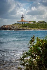 Lighthouse by sea against sky