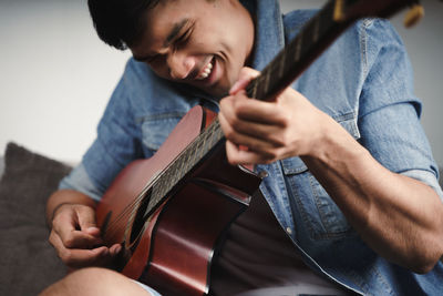 Midsection of man playing guitar