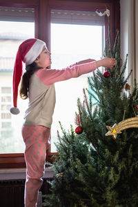 Rear view of woman standing by christmas tree
