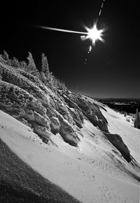 Snow covered land against bright sun