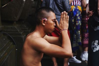 Side view of shirtless man looking at camera