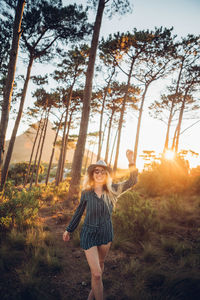 Woman standing against trees during sunset