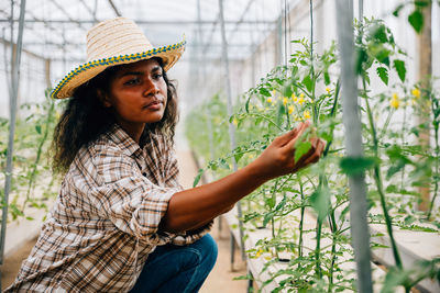 Portrait of young woman standing against plants