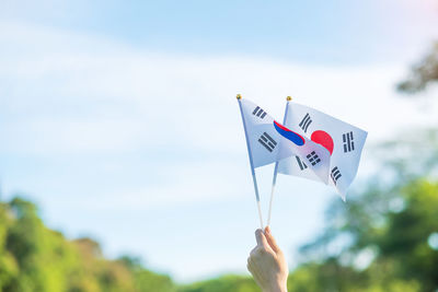 Close-up of hand holding umbrella against sky