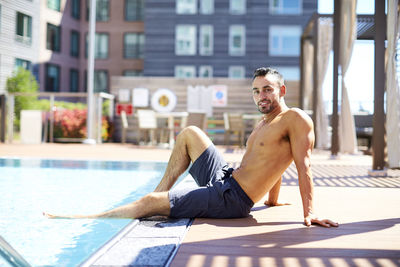 A fit man relaxes by the pool.