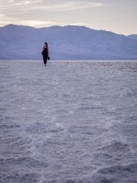 Woman in desert against sky during sunset