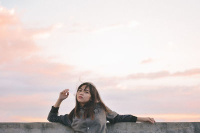 Young woman on beach against sky during sunset