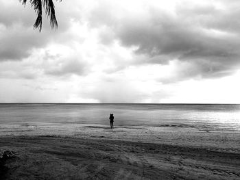 Silhouette people at beach against cloudy sky
