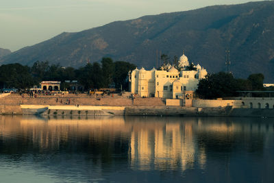 Lake by buildings and mountains in city