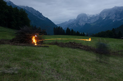 Blurred motion of person burning firewood on field against mountains in winter