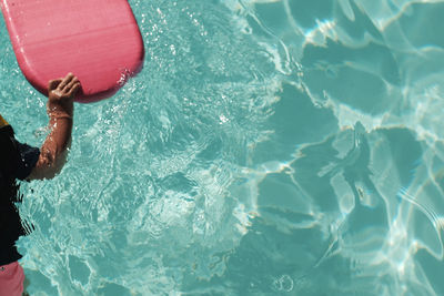 Midsection of child holding pool raft in swimming pool