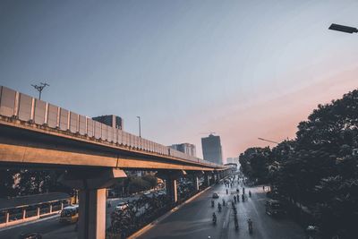 Bridge over street in city against sky at sunset