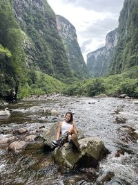 Woman sitting on rock at riverbank