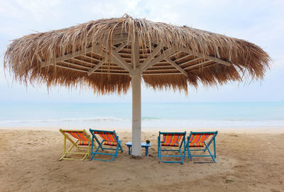 Deck chairs on sand at beach against sky