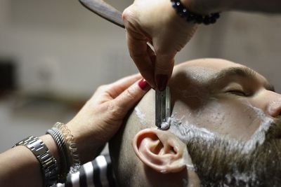 Cropped hands of barber shaving man at salon