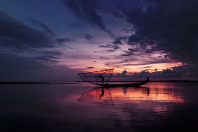 Silhouette fishing boat in sea against sky during sunset