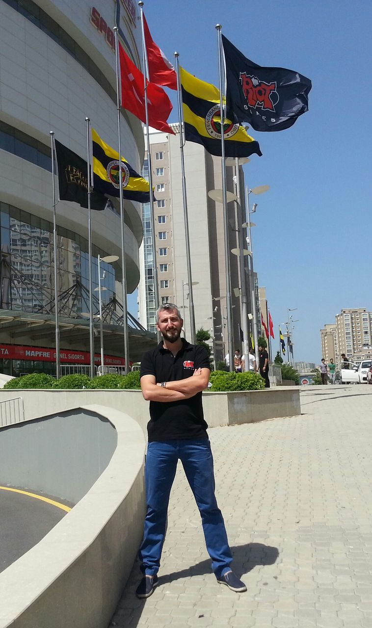 building exterior, architecture, built structure, lifestyles, leisure activity, city, casual clothing, full length, street, flag, men, standing, young adult, person, city life, patriotism, day, clear sky