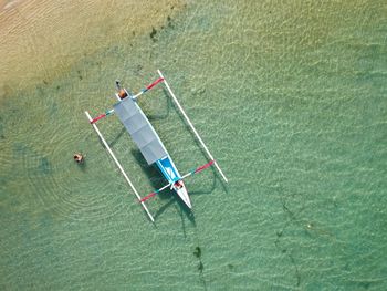 High angle view of outrigger moored at beach during sunny day