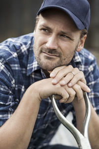 Thoughtful farmer leaning on shovel's handle