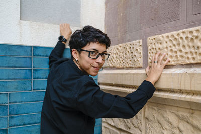 Young transgender person smiling while posing standing outdoors.