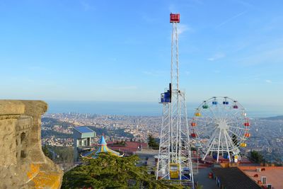 Ferris wheel by sea against blue sky