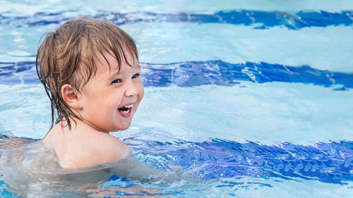 Toddler floats in paddling pool. teaching children to swim from early childhood. copy space.