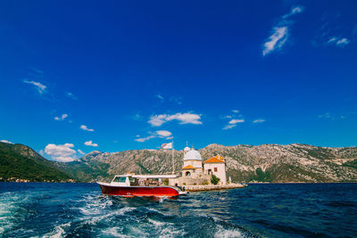 Boat in sea by buildings against blue sky