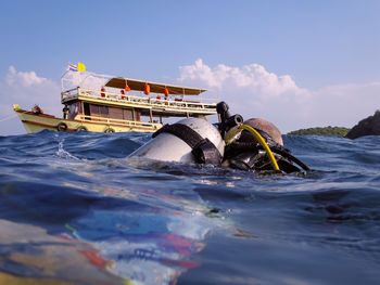 Close-up of person scuba diving in sea against sky