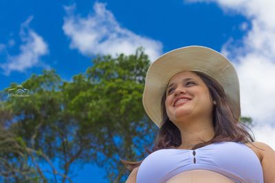 Low angle view of young woman against trees in park