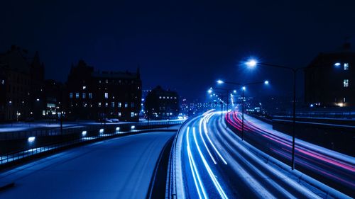 Light trails on road against sky at night