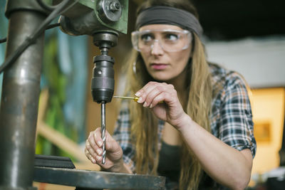 Woman with drill machine working in workshop