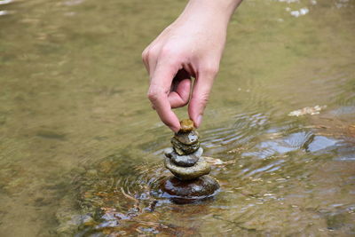 Cropped hand stacking stones in river