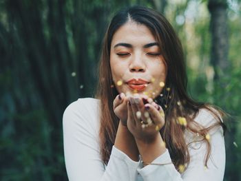 Woman blowing glitters against trees