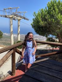Portrait of woman against railing against sky