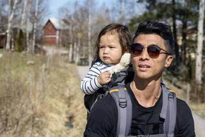 Father carrying daughter in carrier