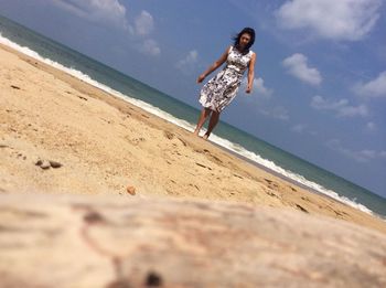 Woman jumping on beach against sky