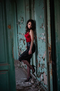 Full length portrait of woman standing against old door