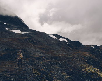 Man walking on mountain against sky