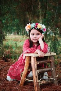 Portrait of casual girl leaning on ladder in forest