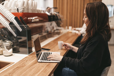 Woman using phone while sitting on table