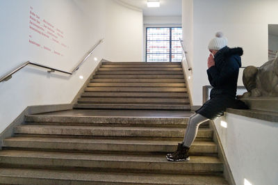 Side view of young woman sitting on steps