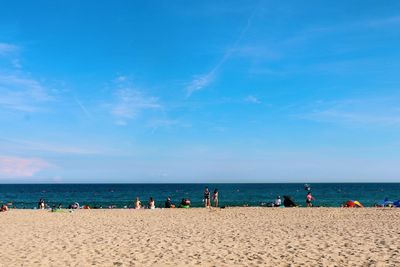 Group of people on beach against blue sky