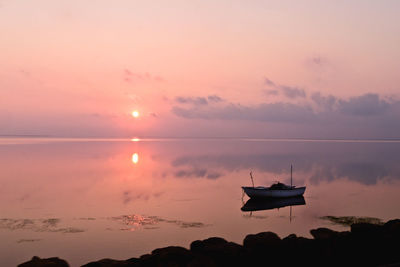 Boat on sea against sky during sunset