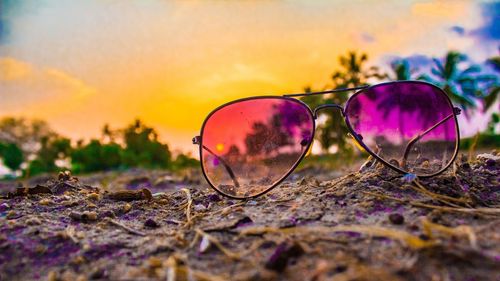 Close-up of sunglasses against sky at sunset