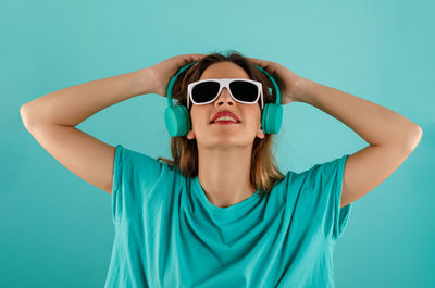 Portrait of young woman wearing sunglasses against blue background