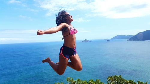 Carefree woman jumping against sea