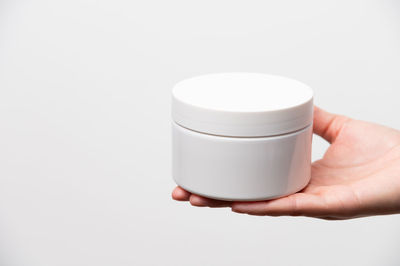Close-up of hand holding coffee against white background
